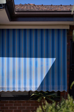 Window awning casting a geometric shadow on a sunny afternoon in a res