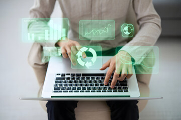 Person using laptop with holographic green carbon emission data graphs and charts.