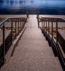 A stone staircase with a handrail leading to the water.