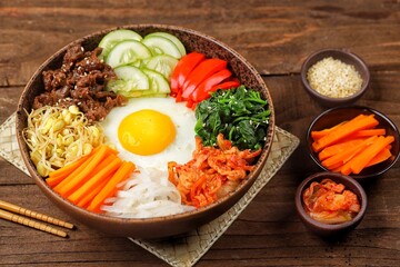 Bibimbap is a Korean dish in the form of a bowl of white rice topped with side dishes of vegetables, beef, eggs and spicy gochujang sauce.