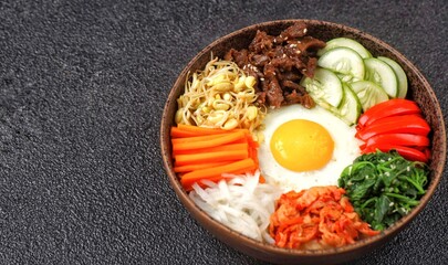 Bibimbap is a Korean dish in the form of a bowl of white rice topped with side dishes of vegetables, beef, eggs and spicy gochujang sauce.