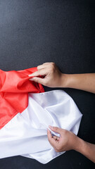 Hands holding red and white flag of Indonesia to celebrate Indonesia independence day isolated on black background