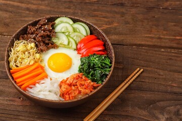 Bibimbap is a Korean dish in the form of a bowl of white rice topped with side dishes of vegetables, beef, eggs and spicy gochujang sauce.
