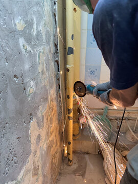 Worker cutting metal pipe with sparks flying indoors
