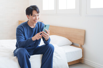 寝室でスマホを使う男性