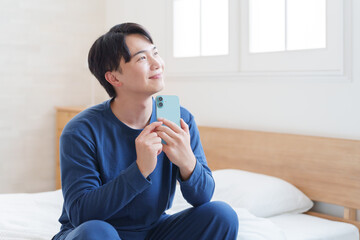 寝室でスマホを使う男性