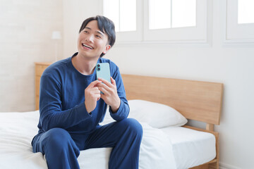 寝室でスマホを使う男性