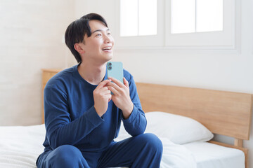 寝室でスマホを使う男性
