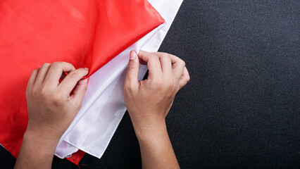 Hands holding red and white Indonesia flag color isolated on black background