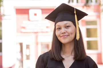Happy young asian woman in graduation gown. 