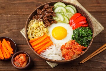 Bibimbap is a Korean dish in the form of a bowl of white rice topped with side dishes of vegetables, beef, eggs and spicy gochujang sauce.