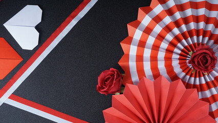 Independence Day Indonesia banner mockup with a rose, Indonesia flag color paper fans, ribbons, and heart shaped origami isolated on black background