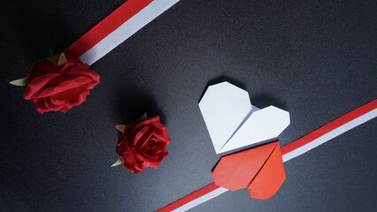 Independence Day Indonesia banner mockup with a rose, Indonesia flag color ribbons and heart shaped origami isolated on black background