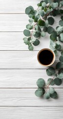 Flatlay of coffee cup and eucalyptus sprigs on white wood