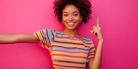 Smiling Woman with Afro Hair Pointing at the Camera, Happy Young Woman with Colorful Striped Shirt, Cheerful Woman Posing in Front of Pink Wall

