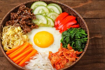 Bibimbap is a Korean dish in the form of a bowl of white rice topped with side dishes of vegetables, beef, eggs and spicy gochujang sauce.