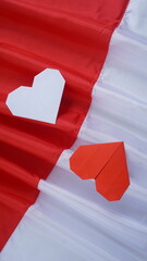 Red and white heart shaped origami on red and white Indonesia flag fabric isolated