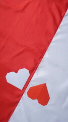 Red and white heart shaped origami on red and white Indonesia flag fabric isolated