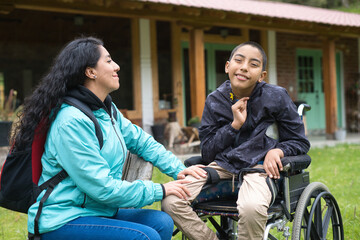 Caring mother supporting her son in wheelchair outdoors