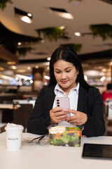 Woman in restaurant having salad and using phone