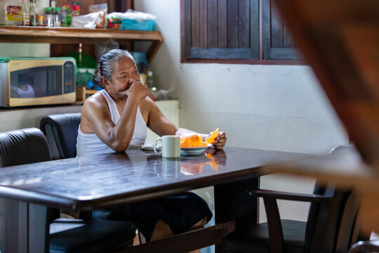 Elderly man quietly enjoying a snack alone in his urban home