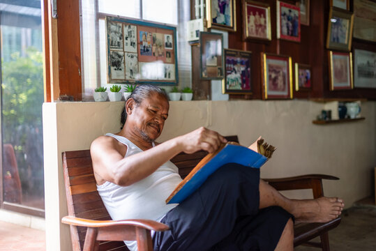 Elderly man reminiscing over old photo album alone at home
