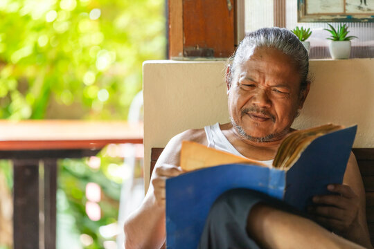 Elderly man reminiscing over old photo album alone at home