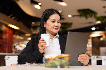 woman in restaurant having coffee while using digital tablet computer and having salad for lunch
