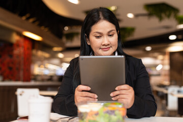 Asian businesswoman drinking coffee in cafe and having salad