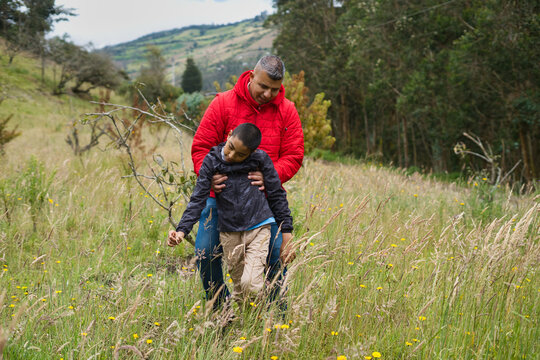Father helping injured son while walking in a field