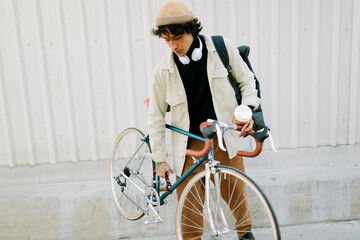Man lifting bicycle with coffee