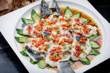 Steamed sea bream with chopped peppers on a black background