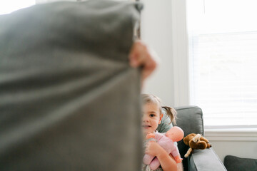 little girl and her baby doll, pillow hiding half her face