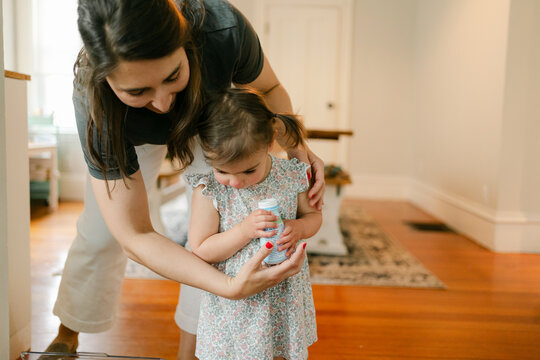 mother helping her little irl to drink a bottle of milk
