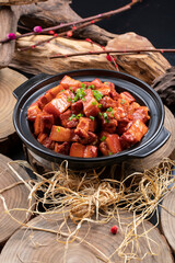 Braised pork in black casserole placed on camphorwood chopping board