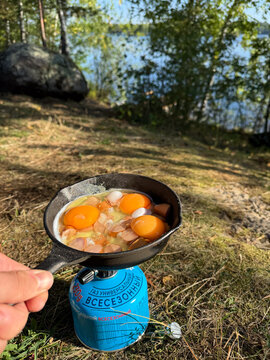 Cooking eggs on portable stove at forest lake camp