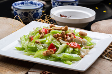 White porcelain plate with cashew nuts, lily and celery