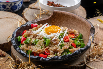 Fried beef with millet and chili sauce in a ceramic dish on a camphorwood chopping board