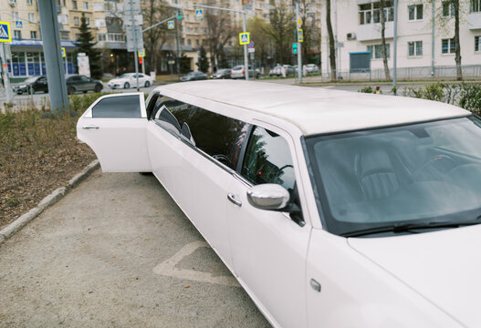 Luxury White Limousine Parked Open Door in Urban City Street Setting