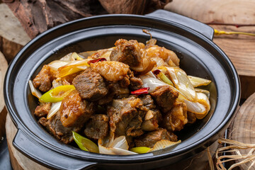 Black casserole with beef shank and green onions