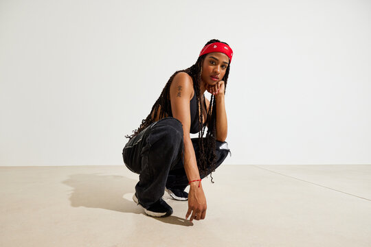Young person squatting in casual attire with a red headband
