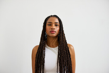 Portrait of a woman with long braided hair against a plain backd
