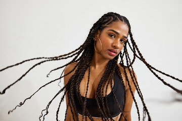Braided-haired woman poses confidently on a white backdrop