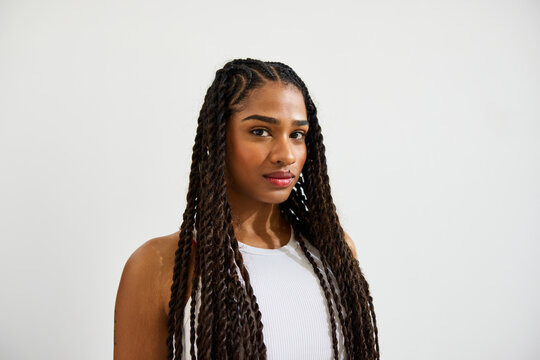 A woman with long braided hair stands elegantly, gazing at the c