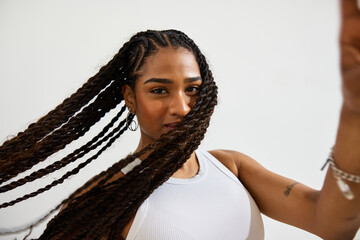 Young woman with braided hair posing against a plain backdrop