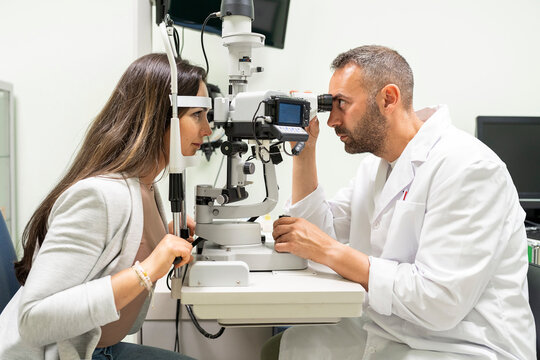 Ophthalmologist performing eye exam on patient using slit lamp