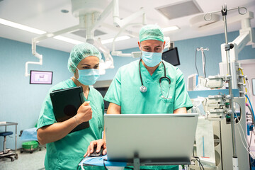 Surgeons using laptop and tablet in operating room