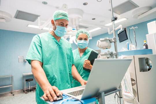 Surgeons using laptop and digital tablet during surgery in hospital