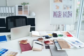 Interior Design Workspace with Material Samples Laptop and Blueprint for Creative Project Planning and Modern Architecture Concepts in Bright Office Setting