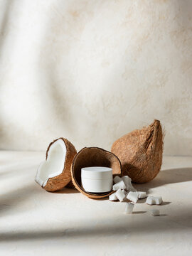 A split coconut shell and a jar of cream. 